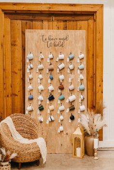 a wall hanging with earrings on it next to a wicker chair and candle holder