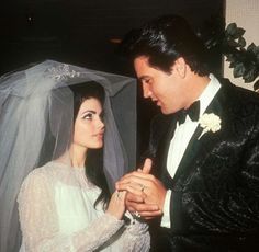 a man and woman standing next to each other in front of a wedding veil on their head