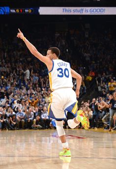 a basketball player is running on the court with his arms in the air as people watch from the stands