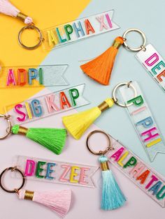 several key chains with letters and tassels attached to them on a colored background