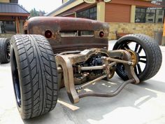 an old car is parked in front of a building with two large tires on it