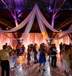 a group of people dancing on a dance floor with white draping and lights