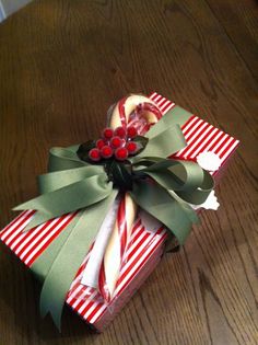 an origami candy cane wrapped in green and red paper on a wooden table