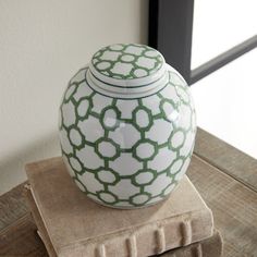 a white and green vase sitting on top of a stack of books