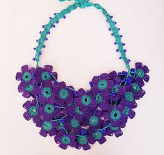 This floral statement necklace is a purple necklace for women and girls. It is crocheted with organic cotton thread. This flower bib necklace is crocheted with love. It is completely our own design. This oya jewelry is made of cotton thread, beads and crochets. It has 4 strands decorated with purple beads. The purple flowers in the necklace are very dense and it makes this beaded crochet necklace dainty. The measures of floral bib necklace are; length 65 cm, height 25 cm and width 16 cm. All connections parts are made of cotton thread. Metal is not used in this purple floral bib necklace. It can be customized in different colors or lengths. This beaded bib necklace is natty and elegant. With crochet oya necklace, you will not need to spend an effort to look sharp. It will look fashionable Handmade Purple Beaded Necklaces For Beach, Handmade Purple Necklaces For Beach, Handmade Purple Beach Necklaces, Adjustable Crochet Flower Necklace, Purple Bohemian Crochet Jewelry, Handmade Purple Flower Necklace For Gift, Adjustable Purple Flower Necklace, Handmade Adjustable Purple Flower Necklace, Handmade Purple Bohemian Flower Necklace