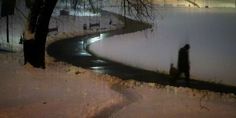 a man walking down a snow covered road at night