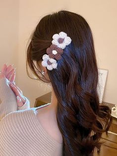 a woman with long brown hair and flowers in her hair is looking at the mirror