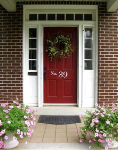 a red door with the number 39 painted on it and some pink flowers in front