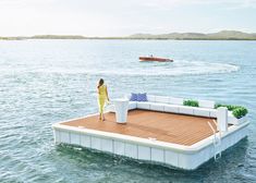 a woman standing on top of a floating bed in the water next to a boat