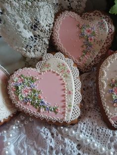 several decorated heart shaped cookies sitting on top of a lace doily covered tablecloth