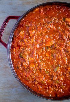 a red pot filled with food sitting on top of a wooden table