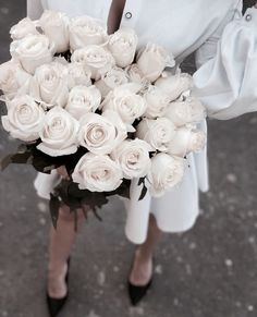 a woman holding a bouquet of white roses