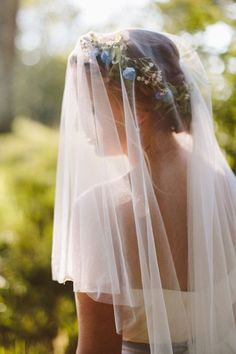 a woman wearing a veil with flowers on it's head and her hair pulled back