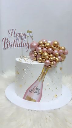 a birthday cake decorated with pink and gold balloons, champagne bottle and wine corks