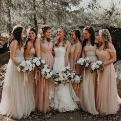 a group of women standing next to each other wearing dresses and holding bouquets in their hands