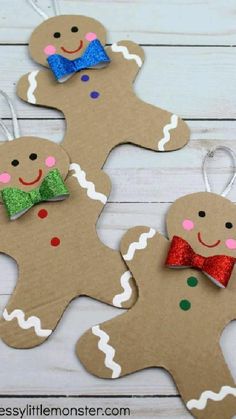 three gingerbread cutouts with bows and glitter bow ties are on a white wooden surface