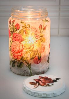 a lit candle sitting on top of a table next to a coaster with flowers painted on it