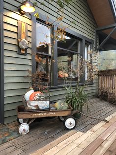 a wheelbarrow filled with pumpkins sitting on top of a wooden deck next to a window