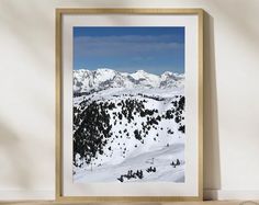 a framed photograph of snow covered mountains in the distance with a wooden frame hanging on a wall