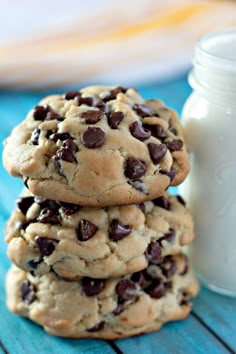 chocolate chip cookies stacked on top of each other next to a bottle of milk and glass of milk