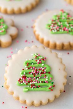 decorated cookies with green icing and sprinkles on a white tablecloth