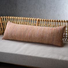 a striped pillow sitting on top of a white couch next to a wicker basket