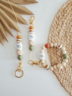 three different keychains with charms on them next to a palm leaf