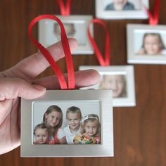 a person holding up a photo ornament with red ribbon around it's edges