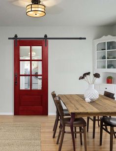 a dining room table with chairs and a red door