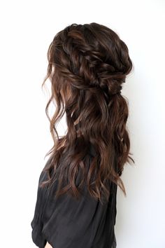 a woman with long dark hair wearing a black shirt and braided in half updo