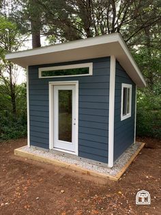 a small blue and white building in the woods