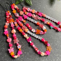 several necklaces are laying on a table next to a plant with flowers in the background