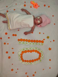 a baby laying on top of a bed covered in orange and white confetti