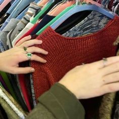 a woman's hand reaching for a ring on top of a sweater in a closet