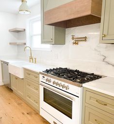 a white stove top oven sitting inside of a kitchen next to wooden floors and cabinets