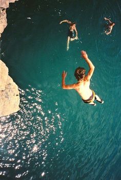 a man is swimming in the water with his hands up and two other people are standing around him