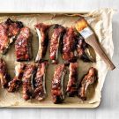 the meat is being prepared and ready to be cooked on the grilling sheet with tongs