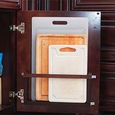 an open cabinet with cutting boards in it