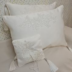 two white pillows with tassels on them sitting on a bed next to each other