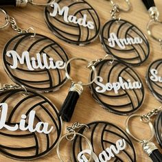 many personalized volleyball key chains on a wooden table with black and white letters that spell out names