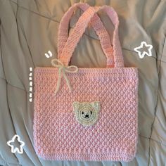 a pink crocheted bag with a teddy bear on the front and side pocket