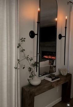 a mirror sitting on top of a wooden table in front of a fire place with candles