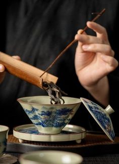 a person holding chopsticks over a tea cup