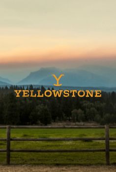 the yellow stone ranch sign is in front of a fence and mountains with trees behind it