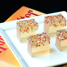 three pieces of cake on a white plate with colorful sprinkles around it