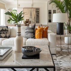 a living room filled with white furniture and lots of plants on top of the coffee table