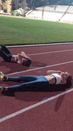 two women laying on the track with their feet up in the air and one lying on the ground