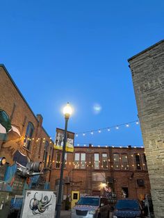 an alleyway with cars parked on the side and buildings in the background at dusk