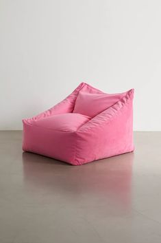 a pink bean bag chair sitting on top of a cement floor next to a white wall