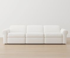 a white couch sitting on top of a hard wood floor next to a white wall